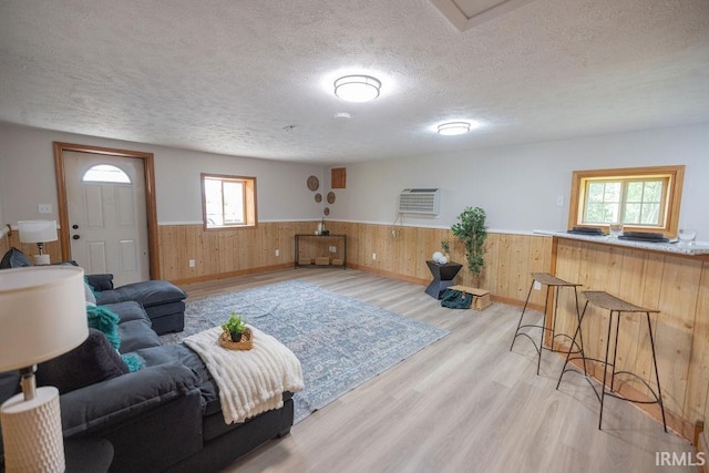 3529 S Walnut St, Muncie, IN 47304 - living room featuring wainscoting, a textured ceiling, light wood-style flooring, and wood walls