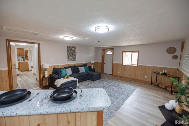 3529 S Walnut St, Muncie, IN 47304 - living room with wainscoting, a textured ceiling, light wood-style floors, and wood walls