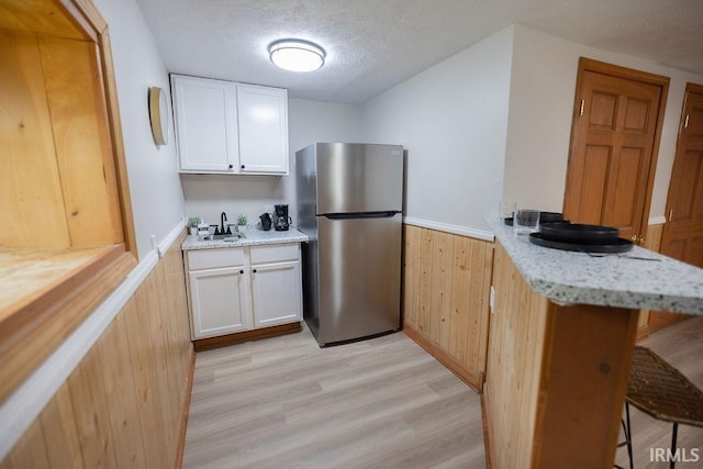 3529 S Walnut St, Muncie, IN 47304 - kitchen featuring freestanding refrigerator, a breakfast bar area, wainscoting, a peninsula, and light wood finished floors