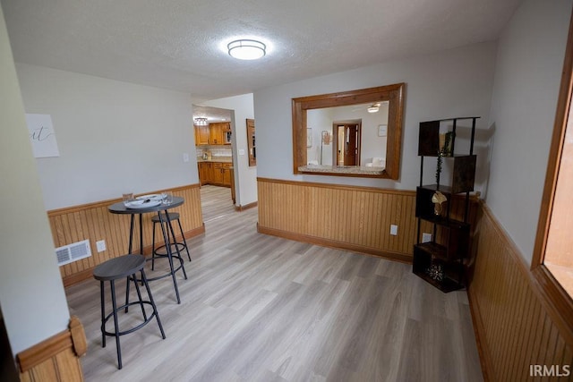 3529 S Walnut St, Muncie, IN 47304 - dining space with a wainscoted wall, a textured ceiling, light wood-style floors, and wood walls