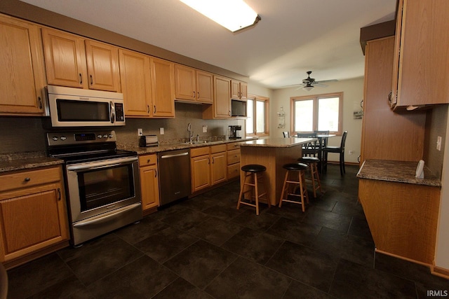 327 Hillside Ave, Roanoke, IN 46783 - kitchen with stainless steel appliances, a kitchen island, a kitchen bar, and a ceiling fan