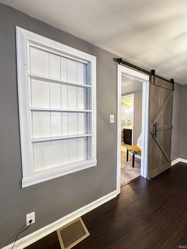 2023 E Columbia St, Evansville, IN 47711 - unfurnished room with a barn door, dark wood-style flooring, and a textured ceiling