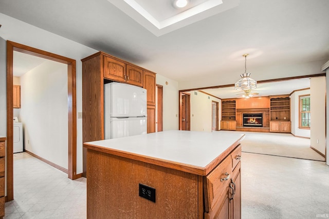 52206 Filbert Rd, Granger, IN 46530 - kitchen featuring freestanding refrigerator, light flooring, washer / clothes dryer, a warm lit fireplace, and brown cabinetry
