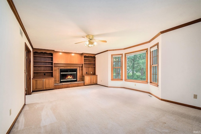 52206 Filbert Rd, Granger, IN 46530 - unfurnished living room with a ceiling fan, crown molding, light carpet, a glass covered fireplace, and built in shelves