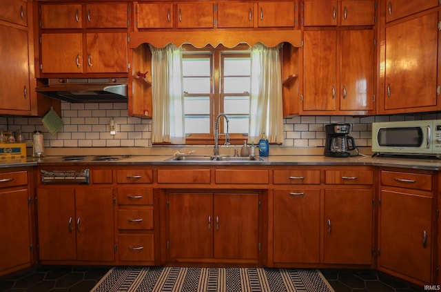 7420 S Fairfax Rd, Bloomington, IN 47401 - kitchen featuring stainless steel microwave, under cabinet range hood, decorative backsplash, dark tile patterned flooring, and brown cabinetry