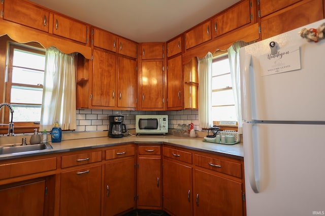 7420 S Fairfax Rd, Bloomington, IN 47401 - kitchen featuring white appliances, backsplash, healthy amount of natural light, and brown cabinets