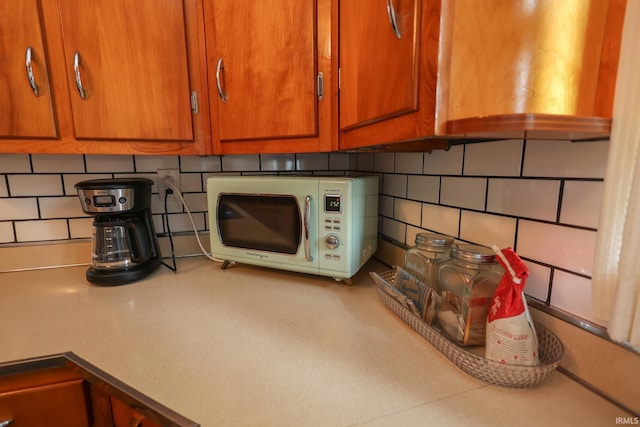 7420 S Fairfax Rd, Bloomington, IN 47401 - kitchen view of white microwave, tasteful backsplash, brown cabinets, and light countertops