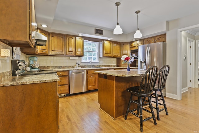 8855 Hickory Ln, Newburgh, IN 47630 - kitchen with appliances with stainless steel finishes, brown cabinetry, light wood-style floors, backsplash, and a kitchen breakfast bar