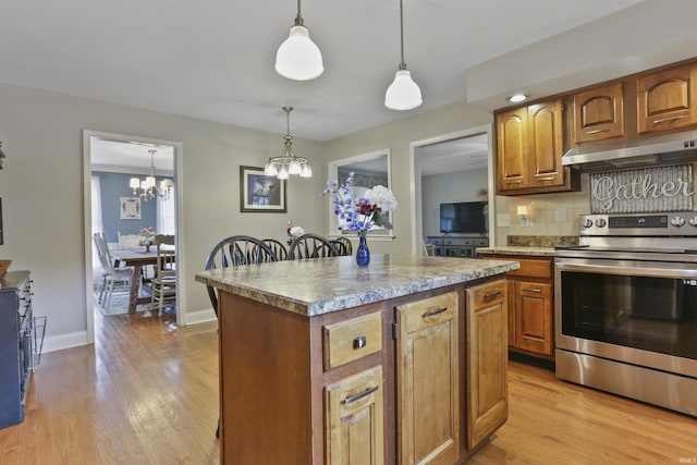 8855 Hickory Ln, Newburgh, IN 47630 - kitchen with stainless steel electric range, under cabinet range hood, a chandelier, a center island, and light wood-style floors