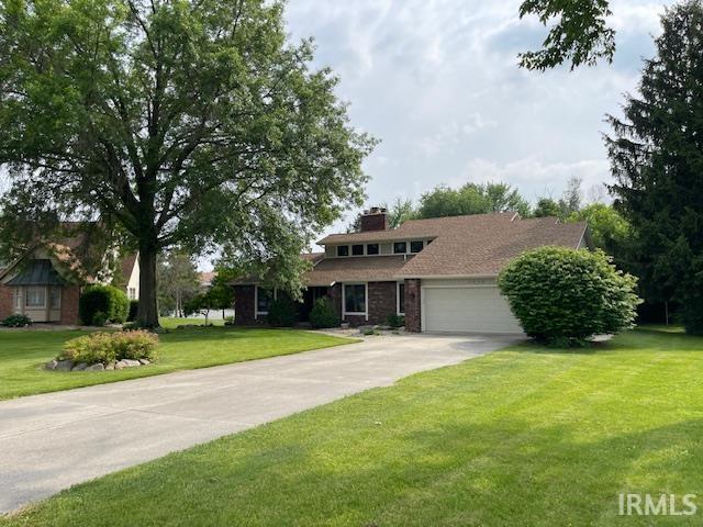 7030 Windshire Dr, Fort Wayne, IN 46814 - view of front of house with a front yard, an attached garage, driveway, a chimney, and brick siding