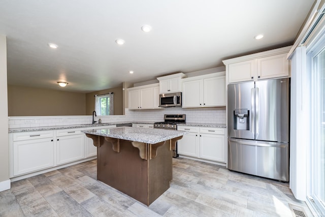 305 Hill Top Ct, New Carlisle, IN 46552 - kitchen featuring appliances with stainless steel finishes, a kitchen island, backsplash, white cabinets, and recessed lighting