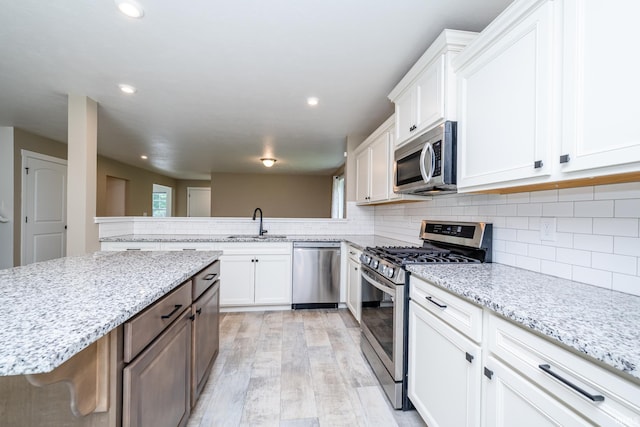 305 Hill Top Ct, New Carlisle, IN 46552 - kitchen with appliances with stainless steel finishes, white cabinetry, light wood-type flooring, light stone countertops, and recessed lighting
