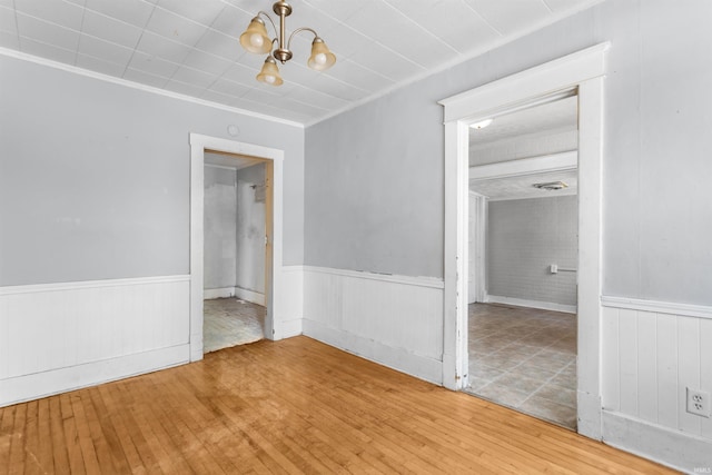 906 S Union St, Kokomo, IN 46901 - unfurnished room featuring wood-type flooring, wainscoting, a chandelier, and crown molding