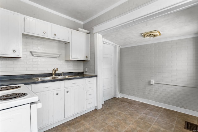 906 S Union St, Kokomo, IN 46901 - kitchen with ornamental molding, white electric stove, dark countertops, white cabinetry, and brick wall