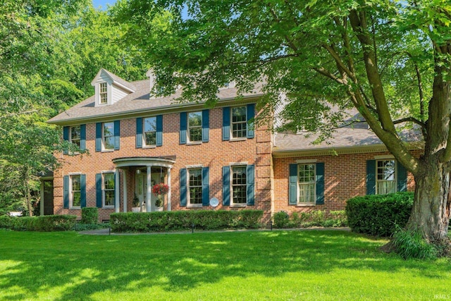 12217 Bay Heights Blvd, Grabill, IN 46741 - colonial-style house with a front yard, brick siding, roof with shingles, and a chimney