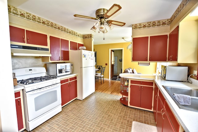 2885 E Bradford Ct, Monon, IN 47959 - kitchen with red cabinetry, white appliances, and under cabinet range hood