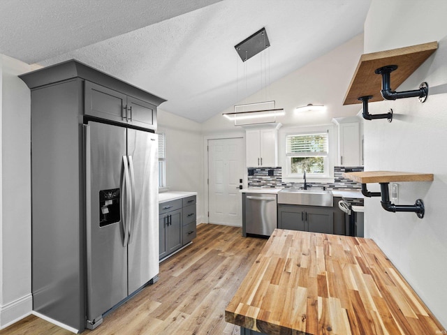 2015 E Blackford Ave, Evansville, IN 47714 - kitchen featuring stainless steel appliances, light countertops, light wood-type flooring, decorative backsplash, and lofted ceiling