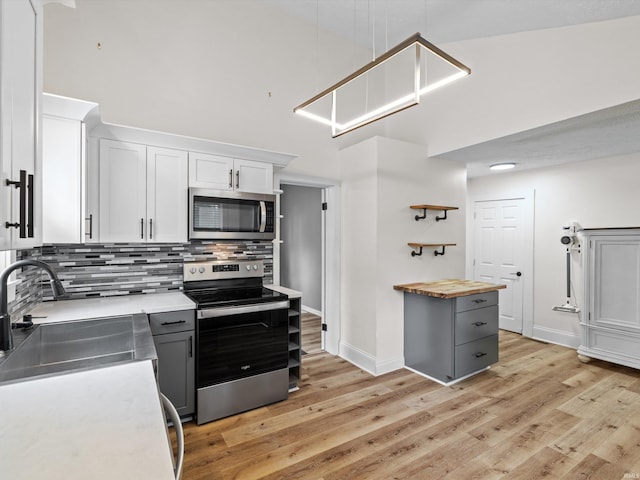 2015 E Blackford Ave, Evansville, IN 47714 - kitchen with appliances with stainless steel finishes, a high ceiling, backsplash, light wood-style floors, and white cabinetry