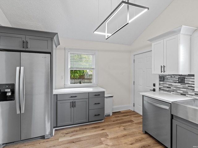 2015 E Blackford Ave, Evansville, IN 47714 - kitchen featuring appliances with stainless steel finishes, gray cabinetry, lofted ceiling, decorative backsplash, and light wood-style floors