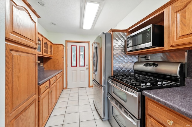 1385 S 460 E, Lagrange, IN 46761 - kitchen featuring stainless steel appliances, dark countertops, glass insert cabinets, tasteful backsplash, and light tile patterned flooring