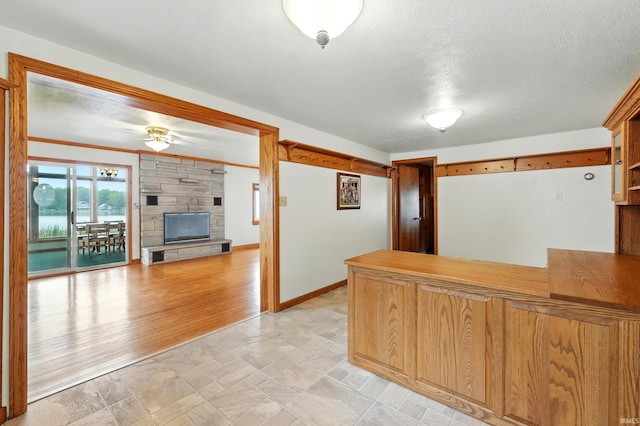 1385 S 460 E, Lagrange, IN 46761 - kitchen featuring a peninsula, a textured ceiling, a stone fireplace, fridge, and a ceiling fan