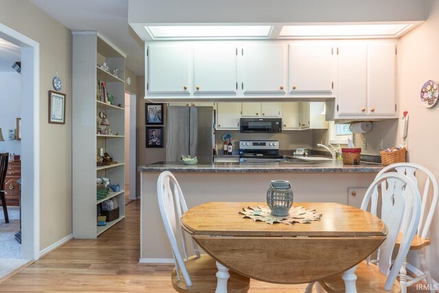 4525 W Middle Ct, Bloomington, IN 47403 - kitchen with stainless steel appliances, dark countertops, light wood-style flooring, and a peninsula