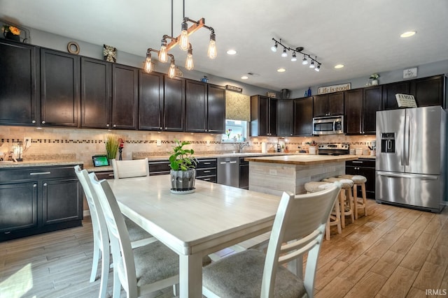 297 Indigo St, Lafayette, IN 47909 - kitchen featuring appliances with stainless steel finishes, light wood-type flooring, a center island, tasteful backsplash, and decorative light fixtures