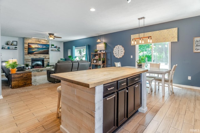 297 Indigo St, Lafayette, IN 47909 - kitchen featuring butcher block countertops, a ceiling fan, light wood finished floors, a stone fireplace, and hanging light fixtures