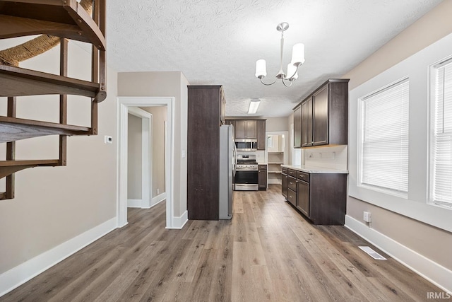 621 S 28th St, Lafayette, IN 47904 - kitchen with appliances with stainless steel finishes, dark brown cabinets, light wood-style floors, a chandelier, and light countertops
