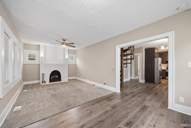 621 S 28th St, Lafayette, IN 47904 - unfurnished living room with wood finished floors, ceiling fan, a textured ceiling, and a brick fireplace