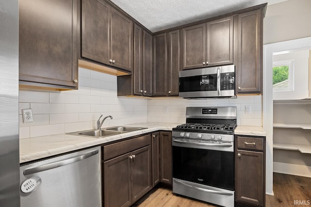 621 S 28th St, Lafayette, IN 47904 - kitchen with appliances with stainless steel finishes, light wood finished floors, dark brown cabinetry, and decorative backsplash