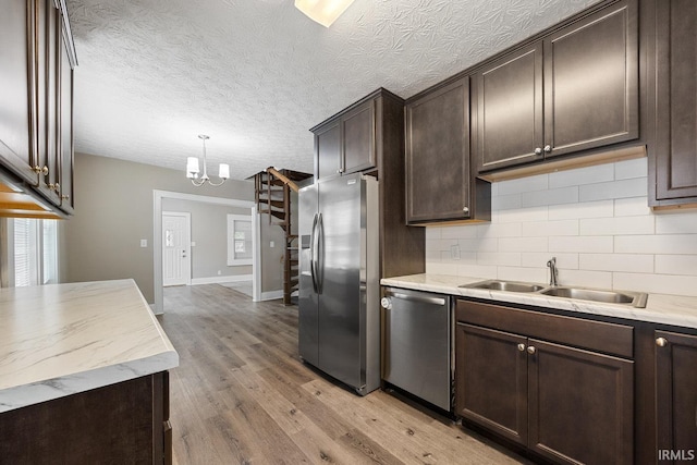 621 S 28th St, Lafayette, IN 47904 - kitchen with appliances with stainless steel finishes, decorative backsplash, dark brown cabinets, light wood-style flooring, and a chandelier