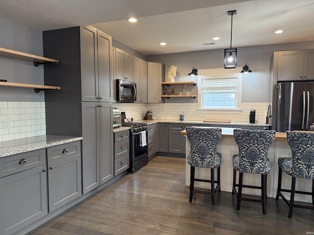 1285 E Zinnia Dr, Bloomington, IN 47401 - kitchen featuring stainless steel appliances, open shelves, gray cabinetry, a kitchen breakfast bar, and backsplash