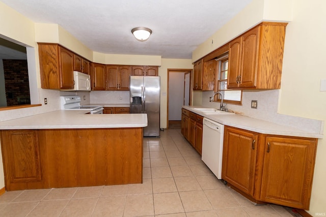 18655 Cleveland Rd, South Bend, IN 46637 - kitchen with white appliances, light countertops, a peninsula, light tile patterned flooring, and brown cabinets