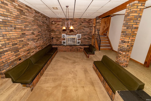 18655 Cleveland Rd, South Bend, IN 46637 - unfurnished living room with brick wall, carpet, a paneled ceiling, and stairs