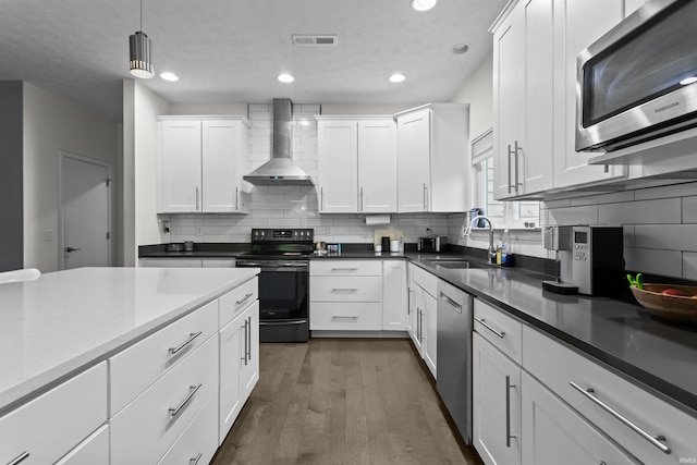 1014 Happy Hollow Rd, West Lafayette, IN 47906 - kitchen featuring wall chimney range hood, appliances with stainless steel finishes, white cabinetry, wood finished floors, and tasteful backsplash