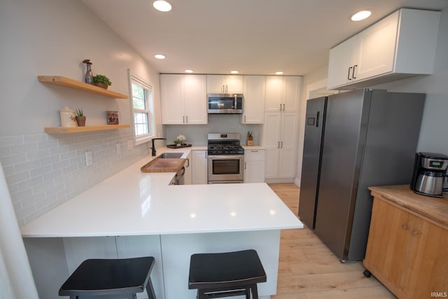 1914 Bayberry Ln, West Lafayette, IN 47906 - kitchen featuring appliances with stainless steel finishes, light wood-style floors, a peninsula, light countertops, and tasteful backsplash