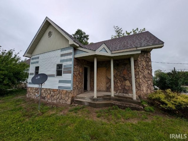 9202 W St, Fairbanks, IN 47849 - view of front facade featuring stone siding, a porch, and a shingled roof