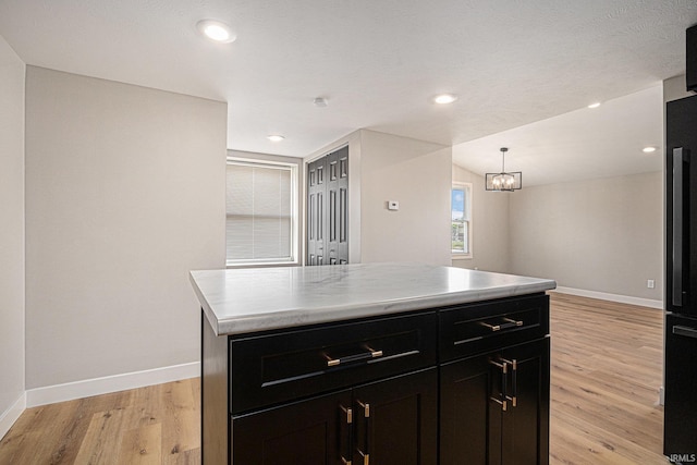 822 W Donaldson Ave, Mishawaka, IN 46545 - kitchen with dark cabinetry, light wood-style flooring, light countertops, a kitchen island, and recessed lighting