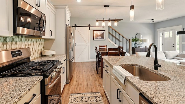 420 Catherwood Dr Unit 3, West Lafayette, IN 47906 - kitchen with stainless steel appliances, a barn door, open floor plan, light wood-style flooring, and white cabinets