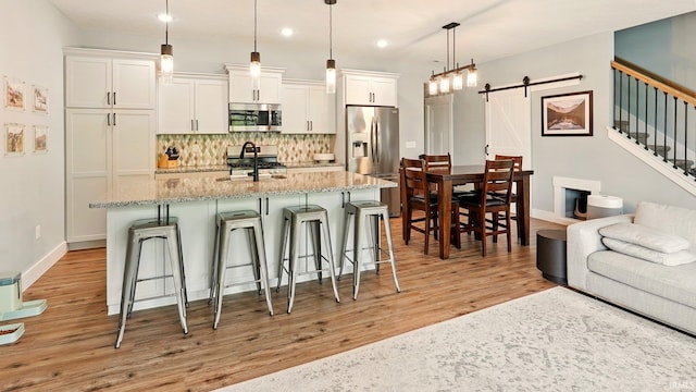 420 Catherwood Dr Unit 3, West Lafayette, IN 47906 - kitchen with stainless steel appliances, a barn door, a kitchen bar, decorative backsplash, and white cabinetry