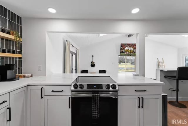 52354 Forestbrook Ave, South Bend, IN 46637 - kitchen with electric stove, a peninsula, light countertops, light wood-style flooring, and vaulted ceiling