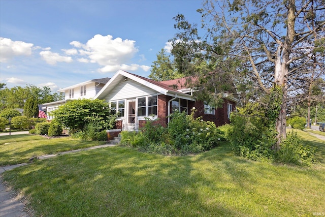 317 N Sunnyside Ave, South Bend, IN 46617 - view of side of home featuring a lawn, brick siding, and a sunroom