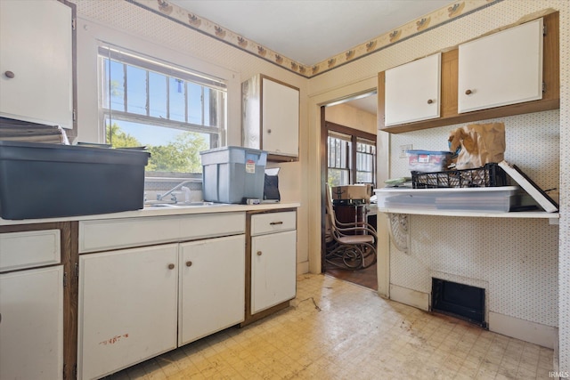 317 N Sunnyside Ave, South Bend, IN 46617 - kitchen featuring wallpapered walls, plenty of natural light, light floors, and white cabinets