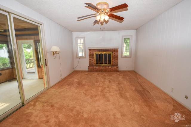 3209 E Kendall Ln, Muncie, IN 47303 - unfurnished living room with plenty of natural light, carpet flooring, ceiling fan, a brick fireplace, and a textured ceiling