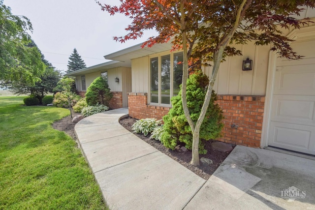3209 E Kendall Ln, Muncie, IN 47303 - view of exterior entry with brick siding, a lawn, and board and batten siding