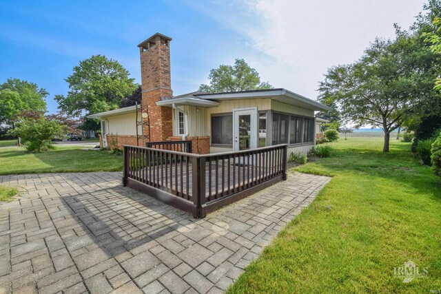 3209 E Kendall Ln, Muncie, IN 47303 - back of property with a chimney, a yard, a sunroom, brick siding, and a wooden deck