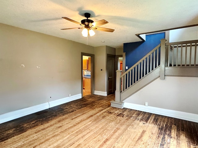 203 E Church St, Milroy, IN 46156 - spare room with a ceiling fan, wood finished floors, stairs, and a textured ceiling