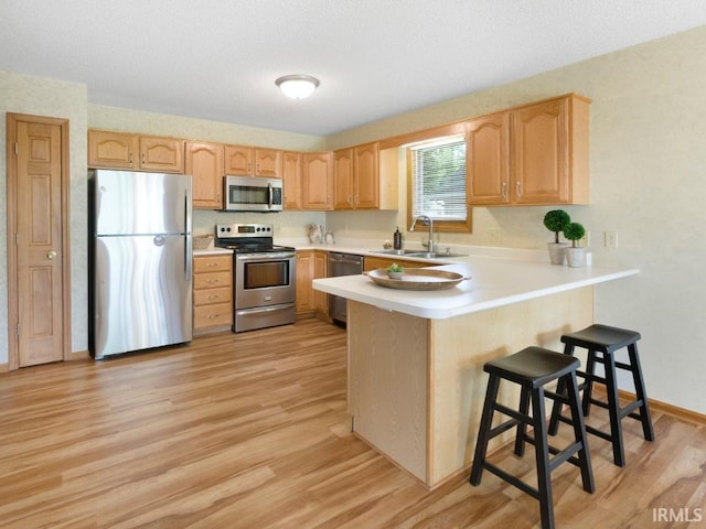 2133 Blue Harbor Dr, Fort Wayne, IN 46804 - kitchen with stainless steel appliances, light brown cabinetry, a peninsula, light wood finished floors, and light countertops