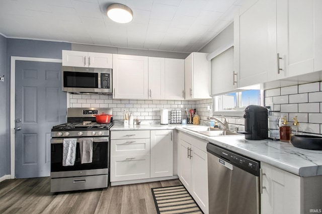 2734 Hawthorne St, Elkhart, IN 46517 - kitchen with stainless steel appliances, white cabinetry, backsplash, light wood finished floors, and light stone countertops